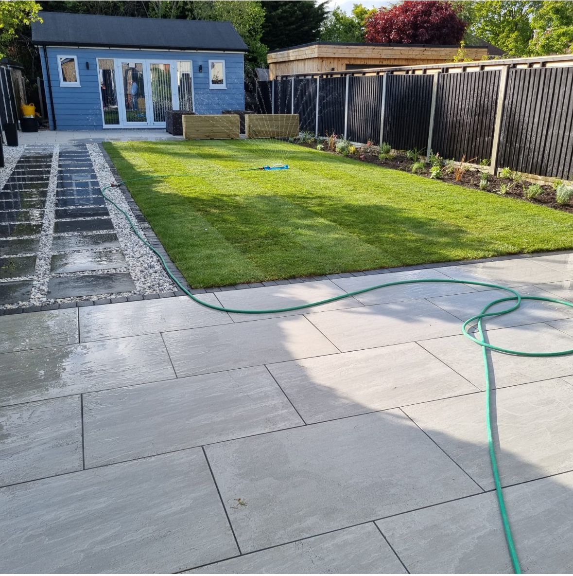 Modern patio with large format slabs, artificial grass, and garden office